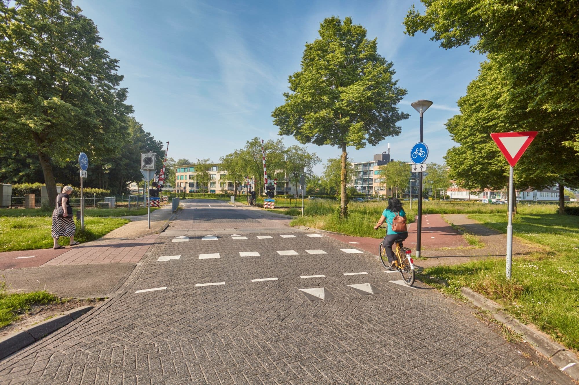 Vrouw op fiets nadert voorrangskruising met haaientanden